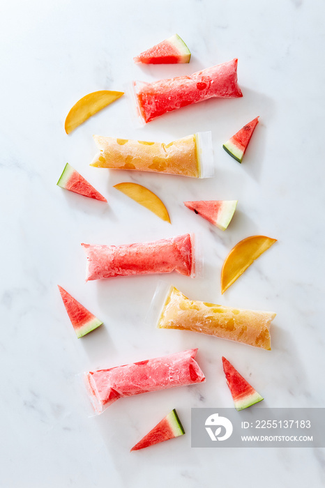 freeze ice pop plastic tube for popsicle packaging with slice watermelon and peach on marble background, top view