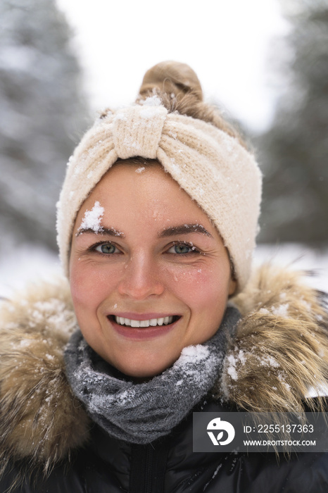 Young cheerful girl enjoying snowfall during beautiful winter day