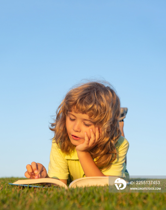 Smart kid boy reading book in park outdoor.