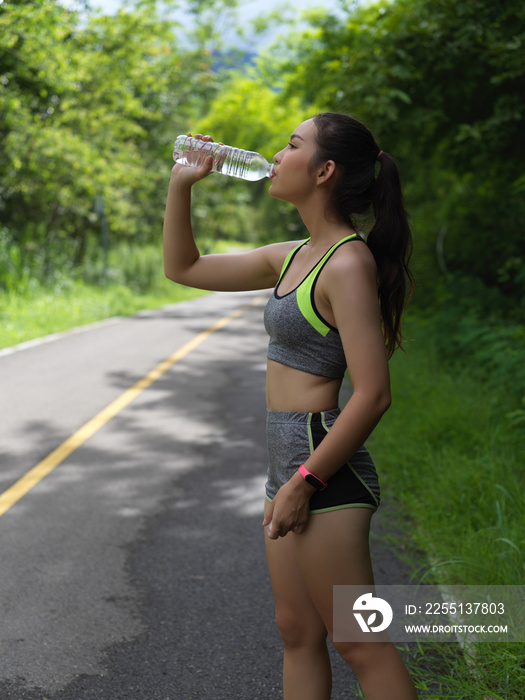 Portrait of female in sport ware drinking water after morning run