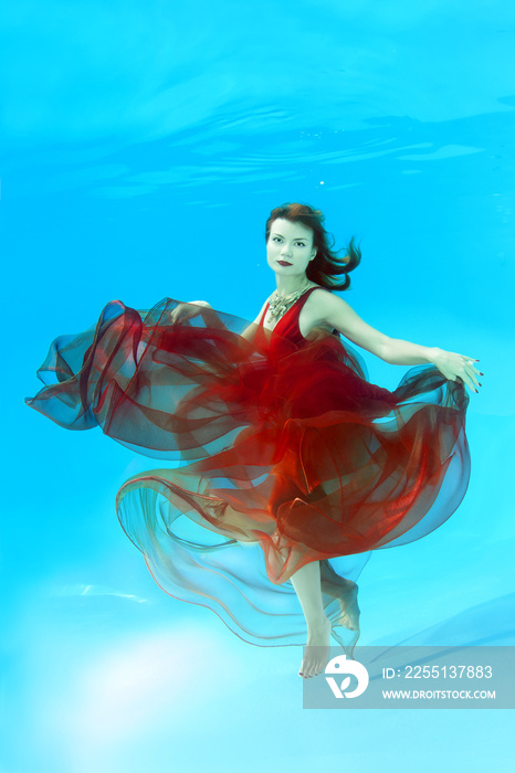 Young beautiful woman with red-haired in a bright dress posing under water (for the calendar, winter, December)