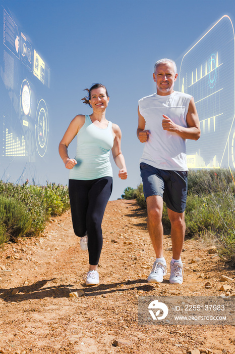 Fit couple running down mountain trail against fitness interface