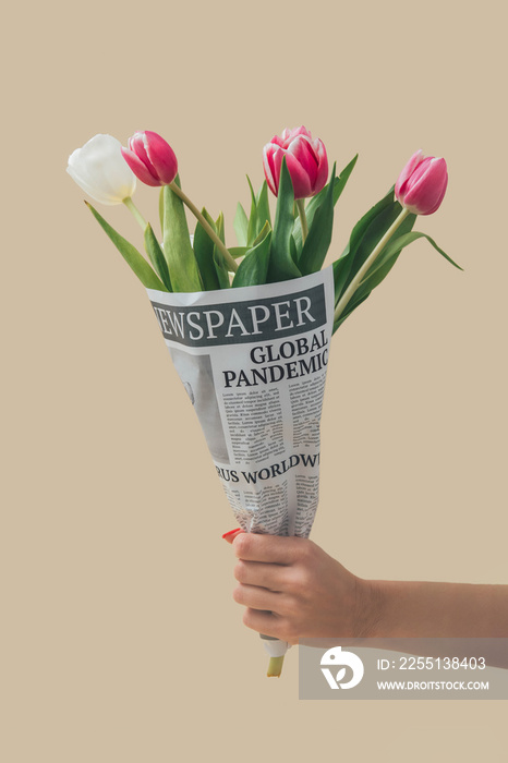 Spring tulips flowers wrapped in newspapers with Global Pandemic headline. Coronavirus disease spring concept. Covid 19 easter background.