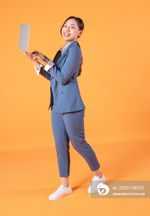 Full length image of young Asian business woman on background