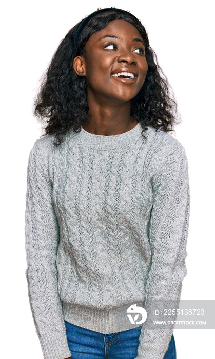 Beautiful african young woman wearing casual winter sweater looking away to side with smile on face, natural expression. laughing confident.