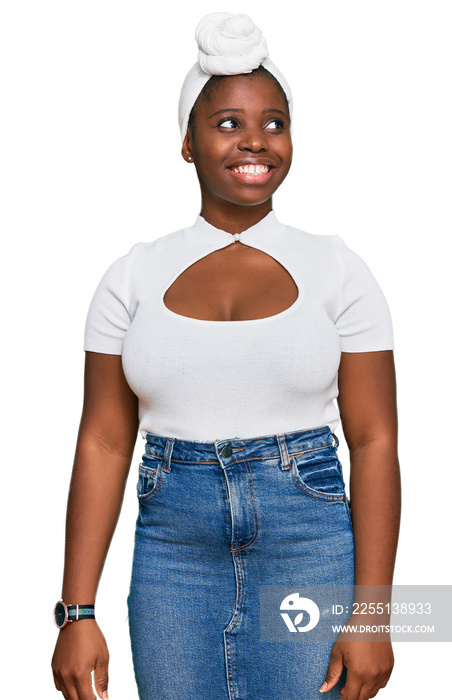 Young african woman with turban wearing hair turban over isolated background looking away to side with smile on face, natural expression. laughing confident.