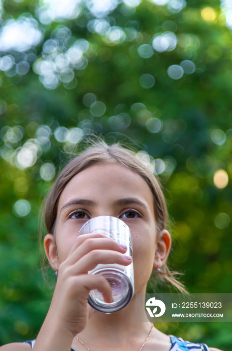 The child drinks water from a glass. Selective focus.