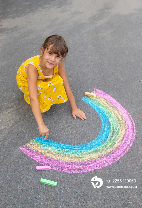 A child draws a rainbow on the asphalt. Selective focus.