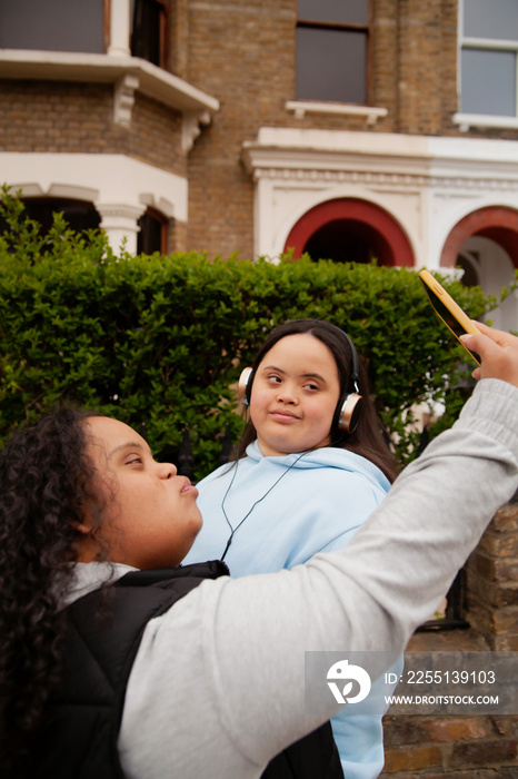 Two curvy women with Down Syndrome taking selfies in with their coffees