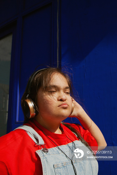 Young curvy woman with Down Syndrome dancing in the sun with headphones