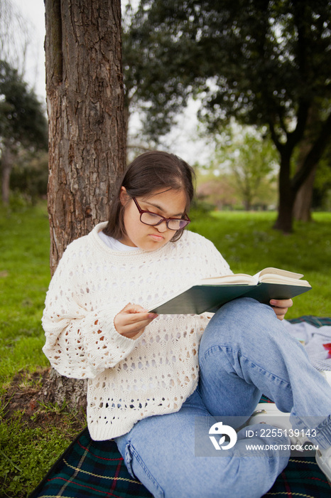 Curvy woman with Down syndrome reading in the park