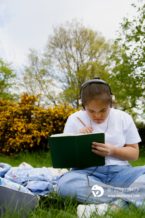 Young mid-sized woman with Down Syndrome listening to music in the park