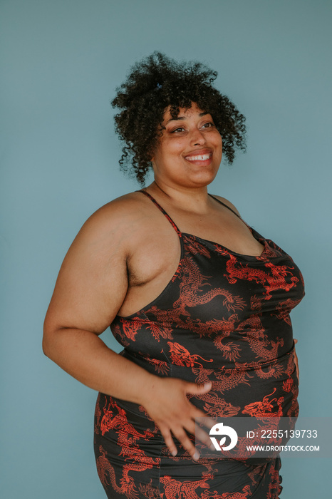 portrait of a plus size afro indigenous person smiling on blue background