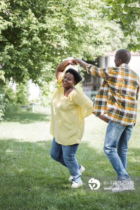 full length of happy senior african american couple dancing in park.