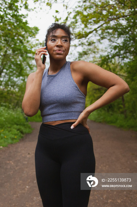 Young curvy woman with vitiligo talking on the phone in workout clothes