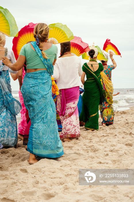 hare krishna women in colorful dresses are walking on the beach in summer