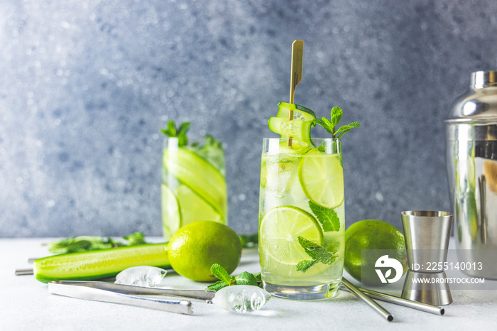 Detox cocktail with mint, cucumber and lime or mojito cocktail in highball glasses on a gray concrete stone surface background.