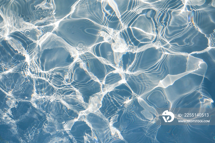 Blue water surface with bright sun light reflections, water in swimming pool background