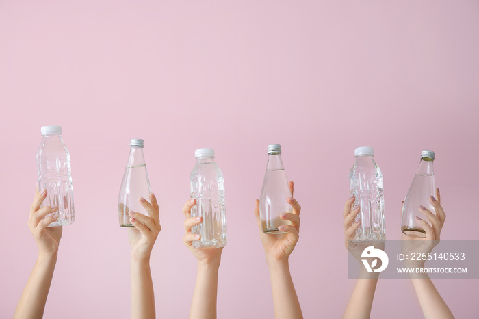 Female hands with bottles of water on color background