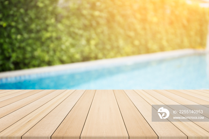 Empty wooden table in front with blurred background of swimming pool