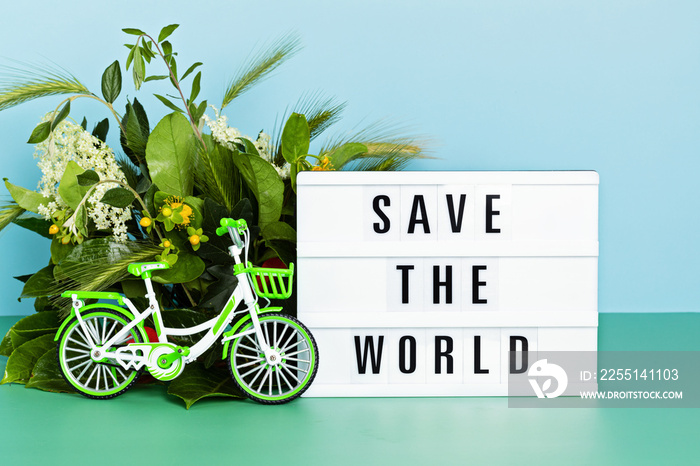 Toy bicycle and lightbox with text save the world. Car free day, world bicycle day, environment protection, sustainable lifestyle concept with copy space