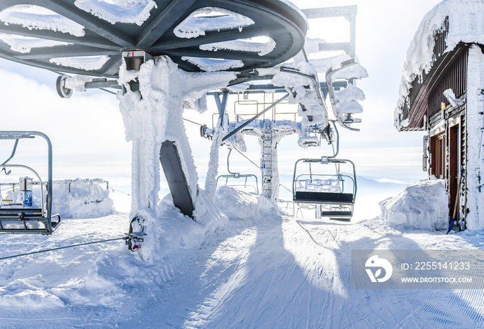 End of ski lifts high in frozen mountains. Winter empty lift seats in sunny holiday.