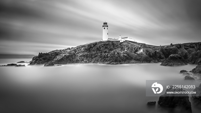 Twilight yields to dawn at Fanad Head Lighthouse. Smudges of clouds and misty water. Black and white long exposure photography with selective focus. Wild Atlantic Way, Donegal, Ireland