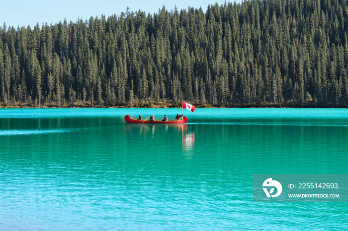 Lake Louise canoeing. Red boat with people holding Canadian flag canoeing in Lake Louise. Banff National Park. Canadian Rockies. Alberta. Canada