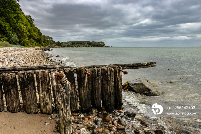 Beach on the Danish Baltic Sea near Sønderborg, Denmark. cloudy sky. In the foreground pier leads into the sea