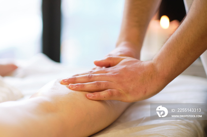 Detail of hands massaging human calf muscle.Therapist applying pressure on female leg. Hands of massage therapist massaging legs of young woman in spa salon. Body care in spa salon for young woman.