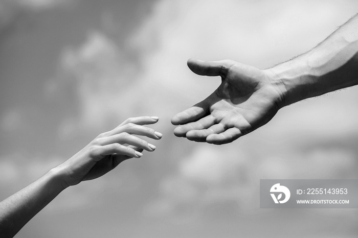 Solidarity, compassion, and charity, rescue. Hands of man and woman reaching to each other, support. Giving a helping hand. Lending a helping hand. Black and white