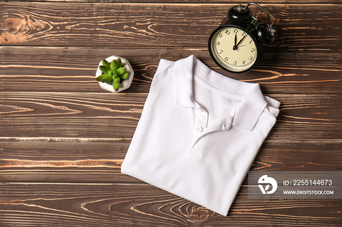 Child t-shirt with alarm clock on wooden background