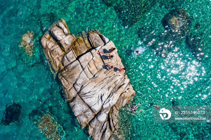 Young people jumping off a stone into the ocean at Fava Beach at Chalkidiki, Greece.