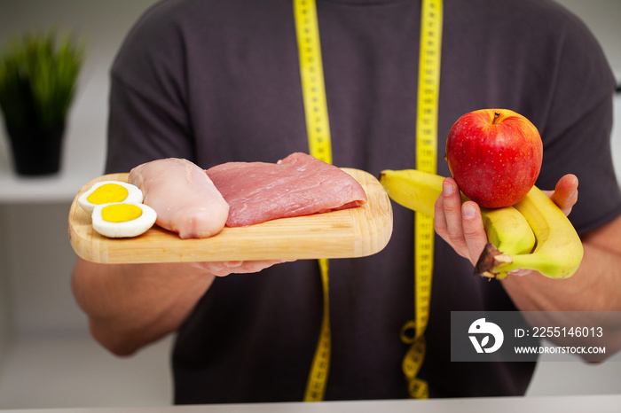 Athletic man holding a board with meat for proper nutrition of the athlete