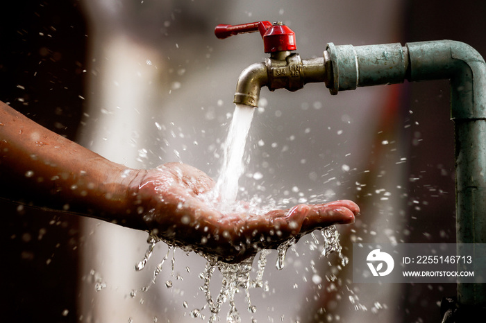 Clean water flows freshly from the tap into the palm of your hand. Focus on the faucet.