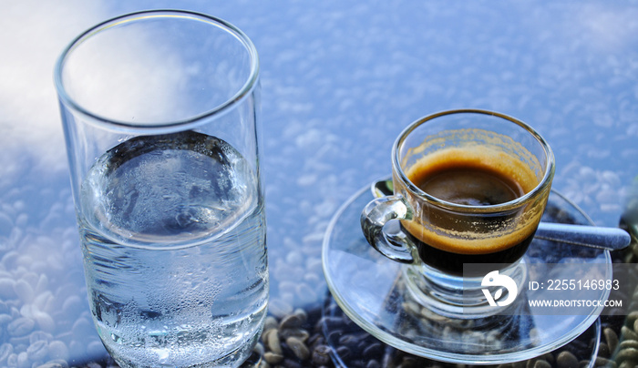 Glass of coffee with drinking water on coffee beans background.