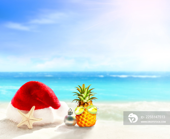 Christmas holidays concept. Santa claus hat and starfish on summer sand beach.