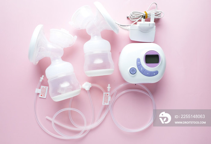 A picture of portable lactation breast pump set on pink background.