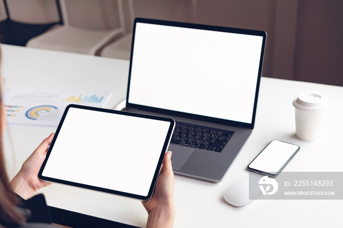 Woman holding tablet screen blank and laptop on the table mock up to promote your products. Concept of future and trend internet for easy access to information.