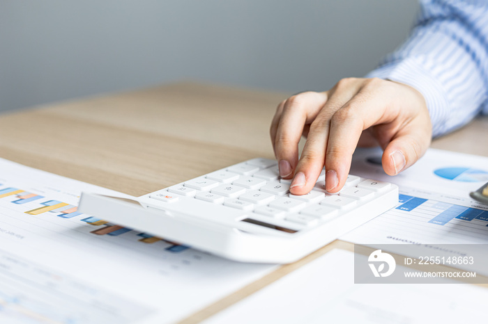 Female auditor pressing white calculator, she is a private company auditor, she is reviewing numbers of company financial statements before presenting them to senior management. Audit concept.