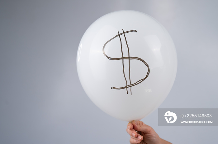 A woman is holding a balloon with a dollar sign. The concept of an inflated currency value.