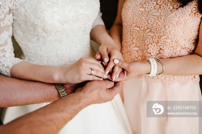 Bride on wedding day holding her mother’s and father’s hands. Concept of relationship between mom, dad, daughter. The mother and father of the bride bless the bride for a happy family life. Close up.