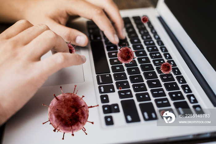 female hands are typing on a laptop, against the background of flying bacteria of the coronavirus. Quarantine Danger