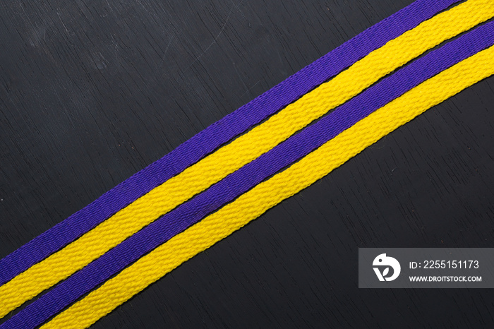 yellow and purple shoelaces, lakers flag, on black wooden background, leaving space for advertising text