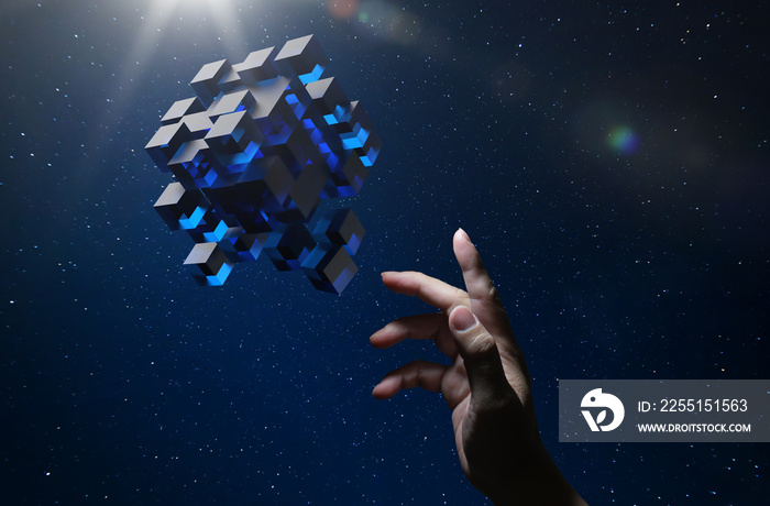 Unknown hand touching floating blue shiny cube on dark background .