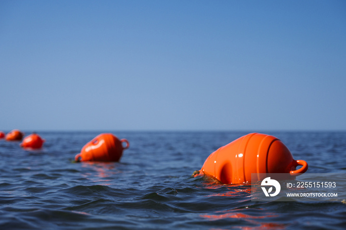 Orange floating buoys in the sea. Human life saving concept. Blue sky.