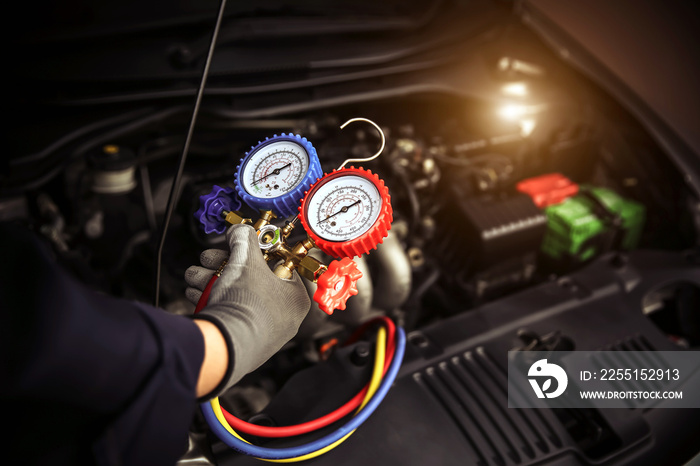 Car care maintenance and servicing, Hand technician auto mechanic using measuring manifold gauge check refrigerant and filling car air conditioner to fix repairing heat conditioning system.