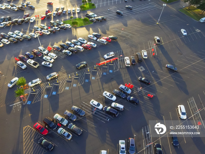 Top view parking lots with rows of parked car, shopping carts, road sign for disabled drivers ata supermarketin Houston, Texas, USA at sunset. Urban infrastructure and transportation concept