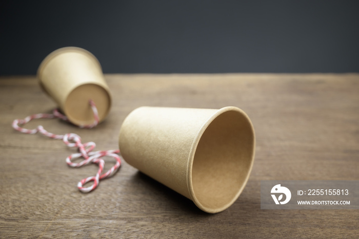 Old style paper cup phone with thread, classic or toy phone on the wood table, two-way communications