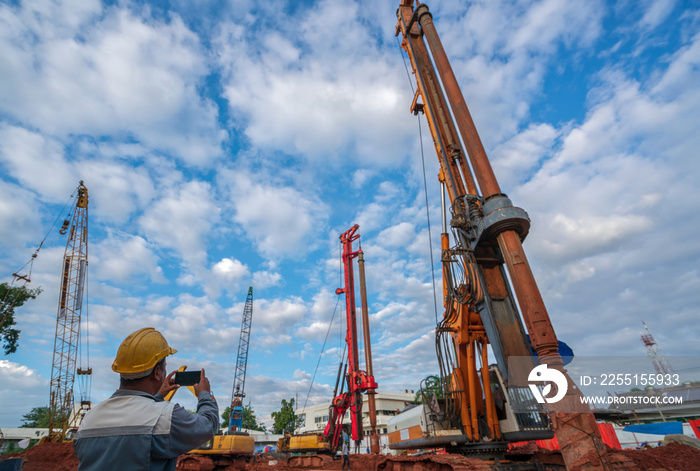 Attractive engineer in uniform with hardhat working checking schedule and take a photo by a smartphone on construction